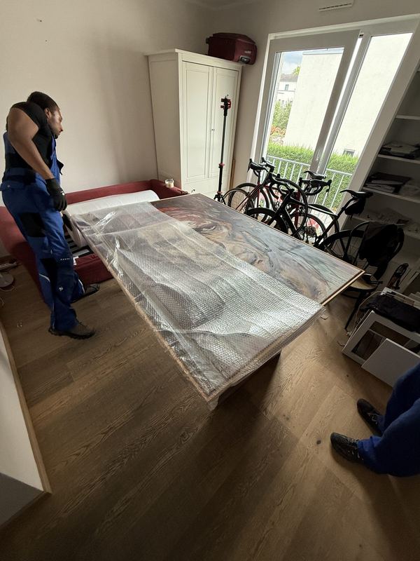 Auf einem Tisch liegt ein großes Bild mit Rahmen, rundum in Luftpolsterfolie gehüllt