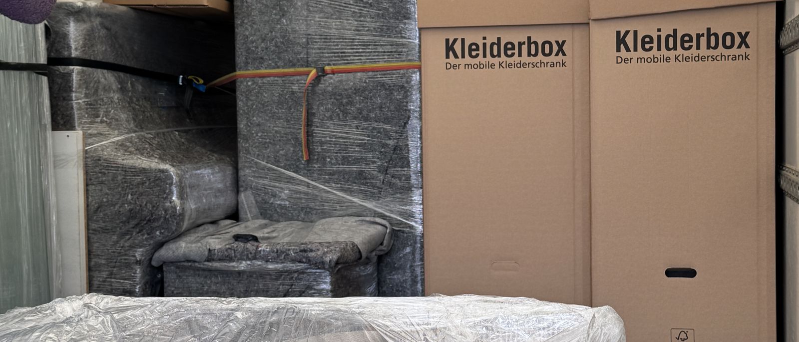 Fernumzug ab Düsseldorf: Kleiderboxen und in Folie gewickelte Möbel dicht gepackt im Laderaum eines Umzugswagens