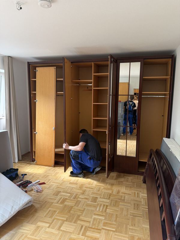 In einem Schlafzimmer richtet ein Mitarbeiter die Türen eines Kleiderschranks mit mehreren Türen aus