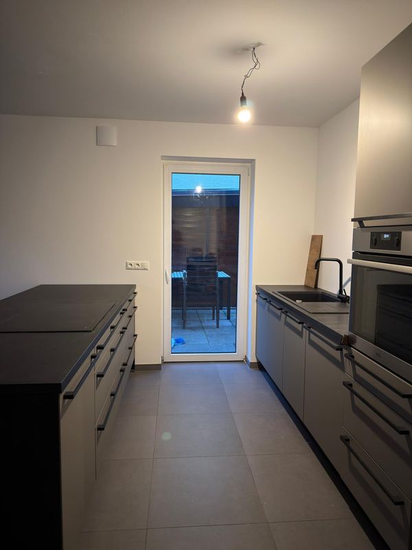 In einem Neubau steht eine fertig aufgebaute Küche mit Kochinsel, die Geräte sind eingebaut