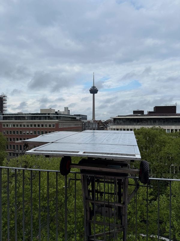 Die Plattform eines Möbellifts in Höhe eines oberen Stockwerks, dahinter ein Fernsehturm