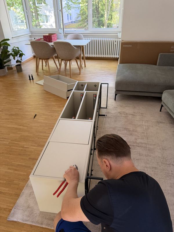 Von oben betrachtet arbeitet ein Mitarbeiter an einem liegenden Sideboard, dessen Schubladenauszüge offen sind