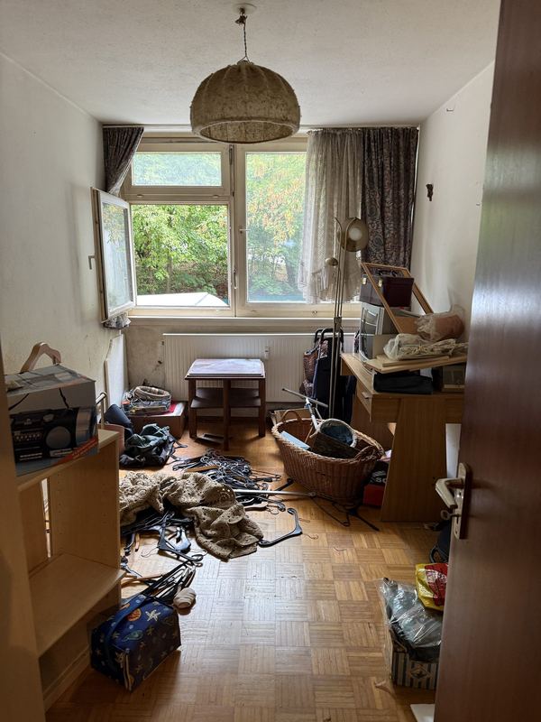Ein Zimmer kurz vor der Räumung, auf dem Boden verteilt liegen Kleiderbügel, Körbe und Kartons